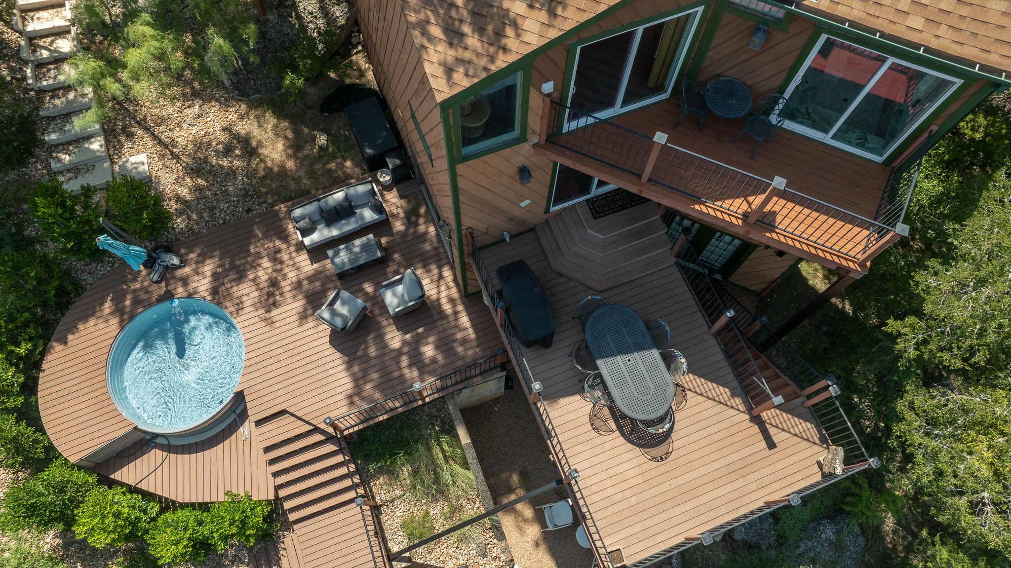 Een huis met twee verdiepingen, een terras, buitenmeubilair en een bubbelbad.