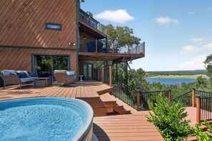 A wooden deck with a pool, outdoor furniture, and a view of a lake. - *New* Hill Country Treehouse Retreat | Pool, Hot Tub & Lake Travis Views ⛰️🌊 (Spicewood)