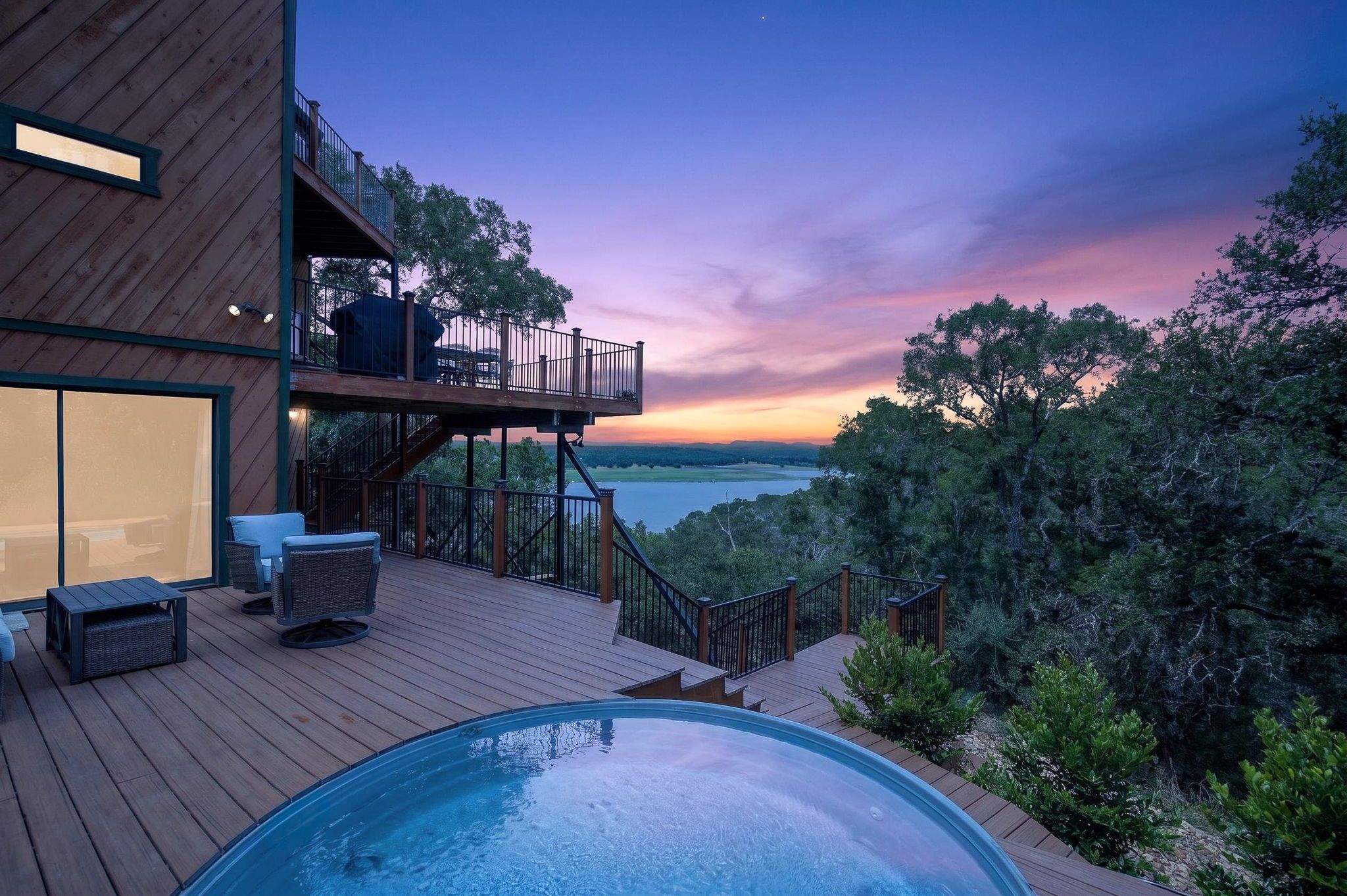 A modern outdoor deck with a hot tub, seating, and a view of the landscape.