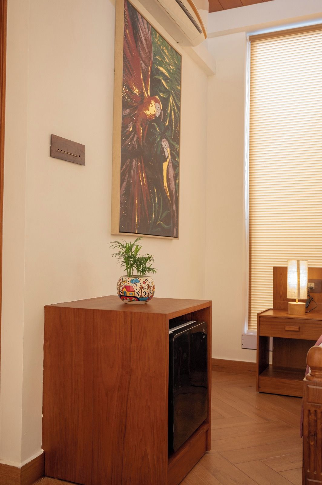 Un meuble en bois avec un lave-vaisselle intégré, une plante aux couleurs vives et un tableau accroché au mur.