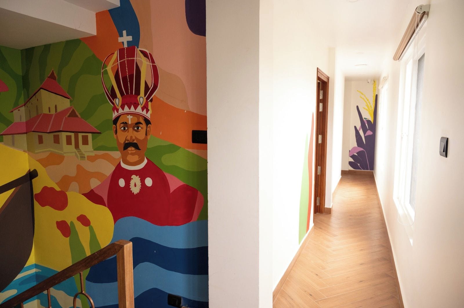 Un couloir orné d’une fresque colorée sur le mur de gauche et doté d’un plancher en bois sur le côté droit.