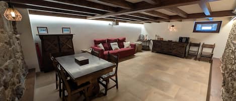 Une pièce avec une table en bois, un canapé rouge et un téléviseur fixé au mur.