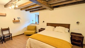 A bedroom with a large bed, wooden headboard, a chair, bedside tables, and a window.