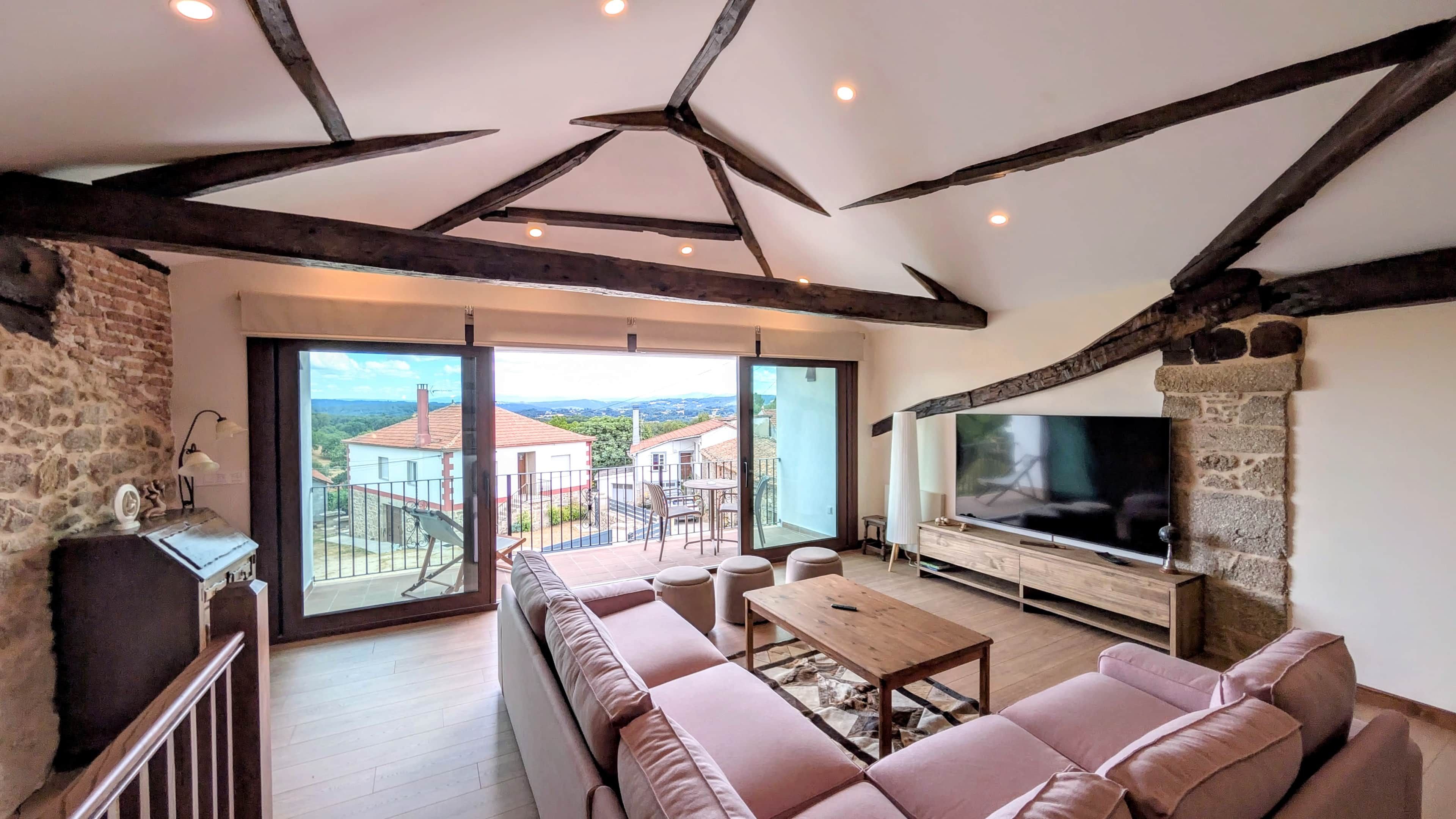 Een ruime woonkamer met een grote televisie, comfortabele zithoek en een balkon met een mooi uitzicht.