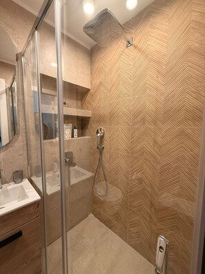 Ein modernes Badezimmer mit Glasdusche, Waschbecken und einem Waschtisch mit Stauraum.