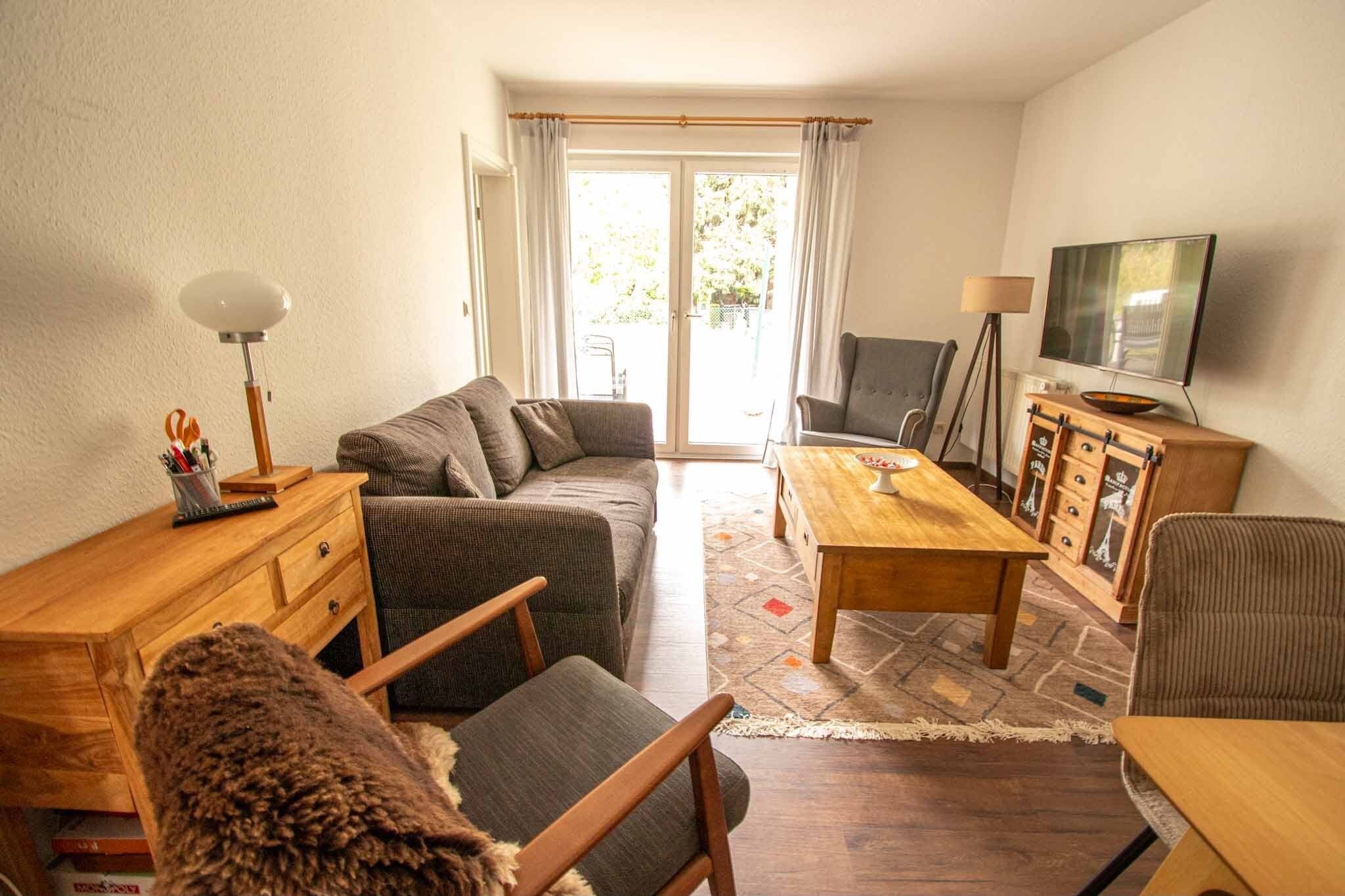 Ein Wohnzimmer mit einer Couch, einem Holztisch, einem Fernseher und einer Lampe.