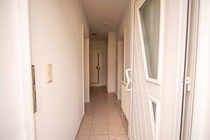 Un passadís amb una porta al final, un interruptor de llum i un radiador a la paret.