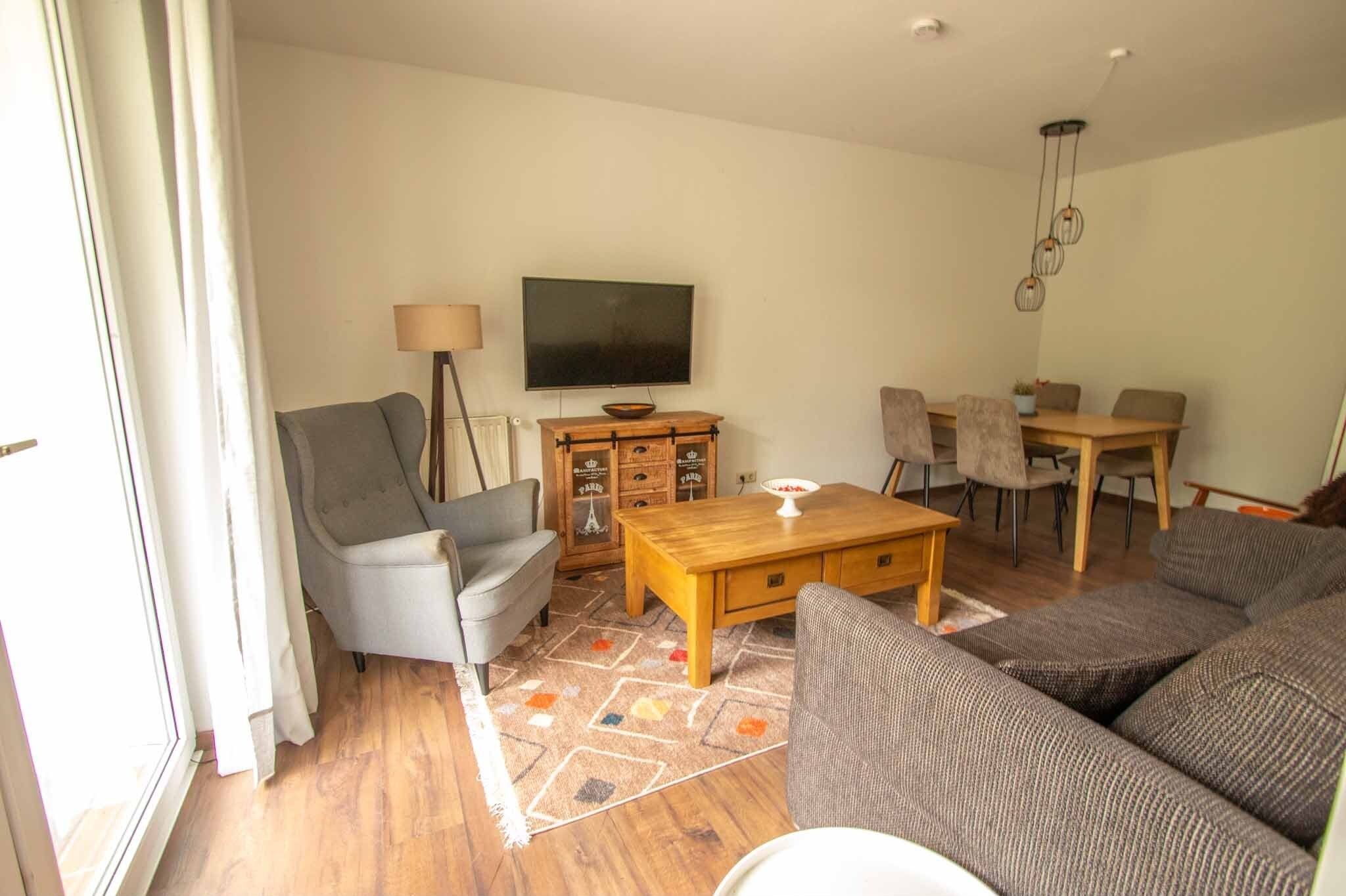 Un salon comprenant un canapé, un fauteuil, une table basse, un téléviseur, ainsi qu’un coin repas avec des chaises et une table.