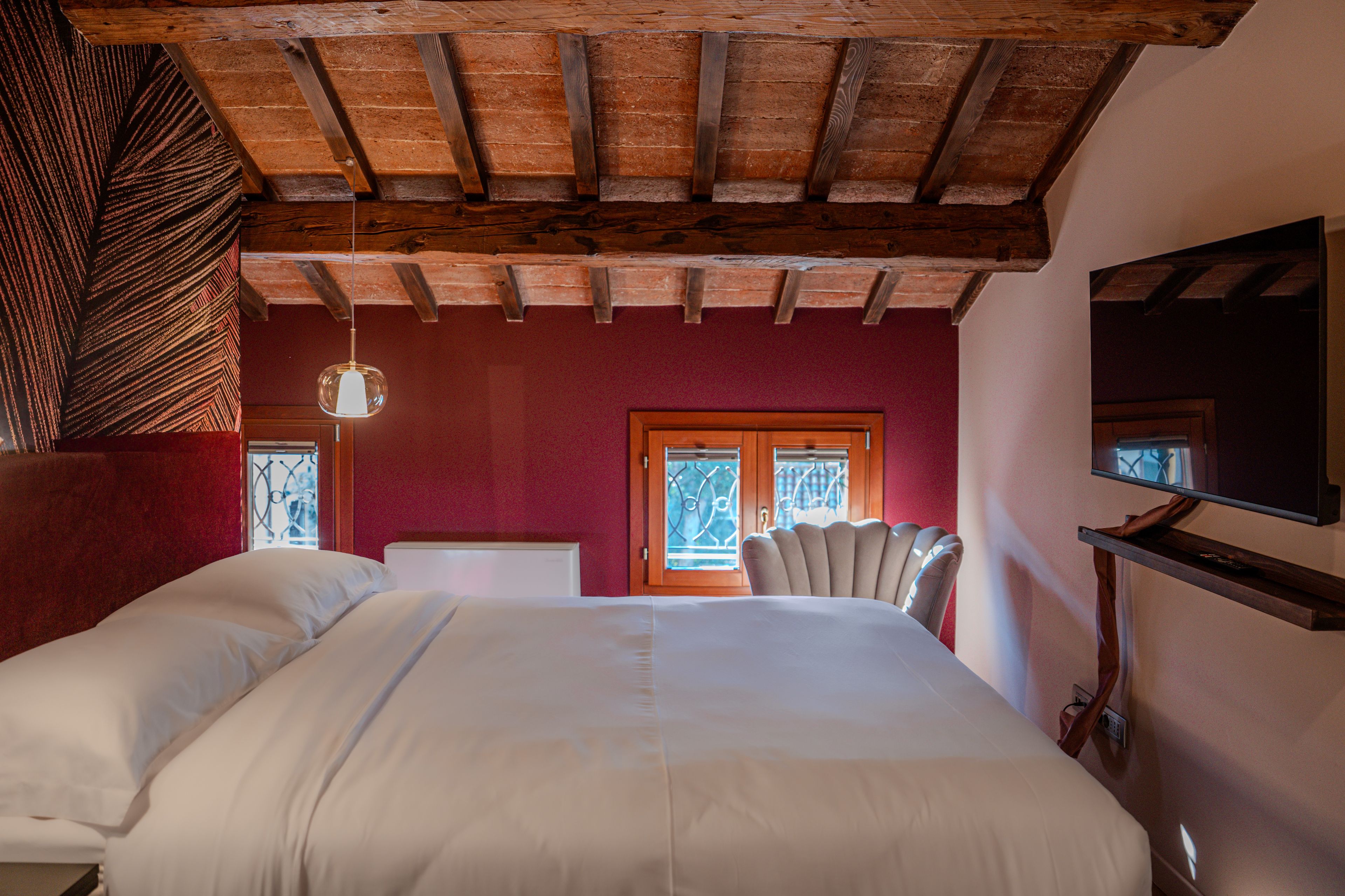 Un dormitorio con una cama grande, un televisor montado en la pared y un ventanal con vistas.