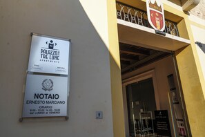 Entrada d'un edifici amb un rètol que indica 'Palazzo delle Tre Lune Apartments' i 'Notaio Ernesto Marciano', i l'horari d'obertura.