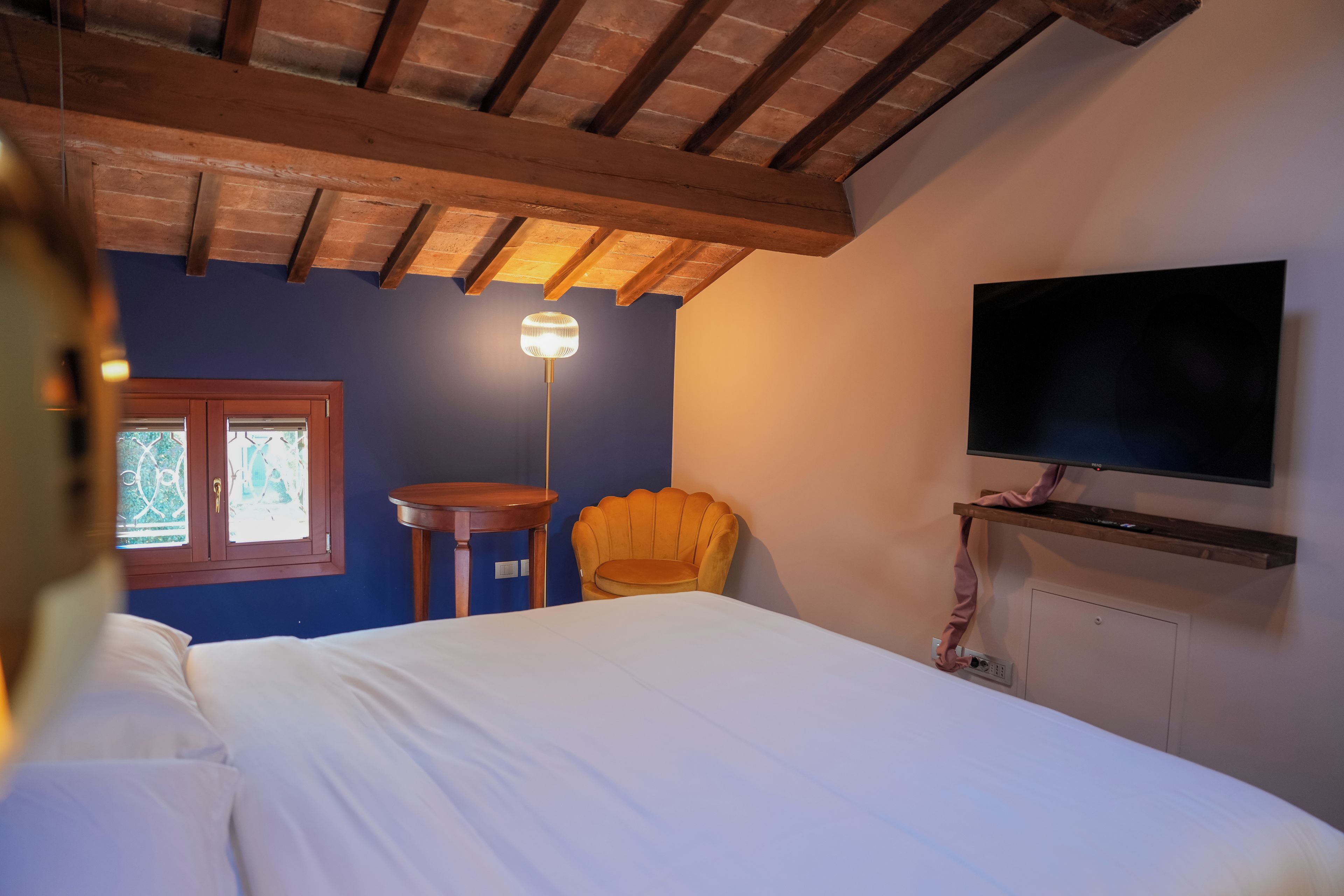 Une chambre à coucher avec un lit, une chaise, une table, un téléviseur et une fenêtre.