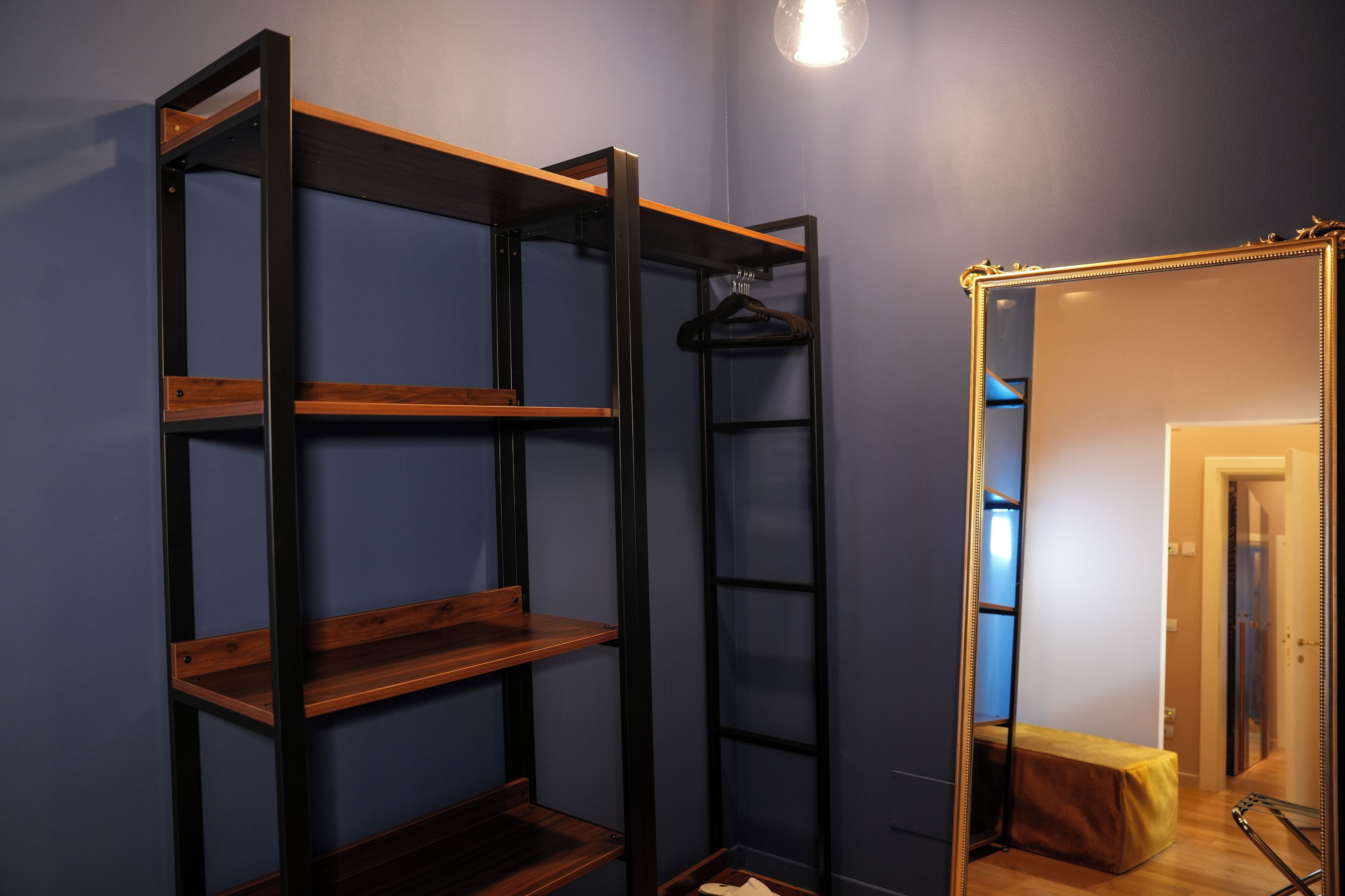 Een kamer met een houten kast, een spiegel met gouden lijst en een kapstok.