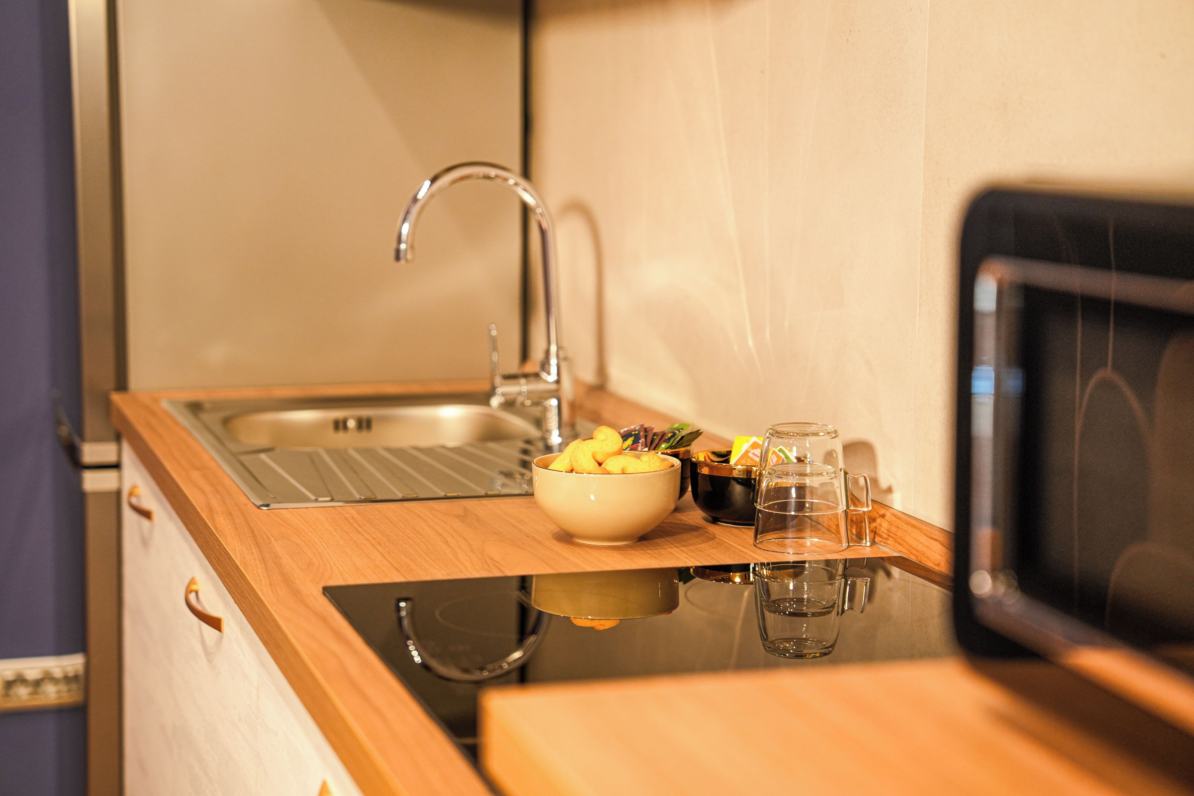 Une petite cuisine équipée d’un évier, d’un bol rempli d’en-cas et d’un four à micro-ondes.
