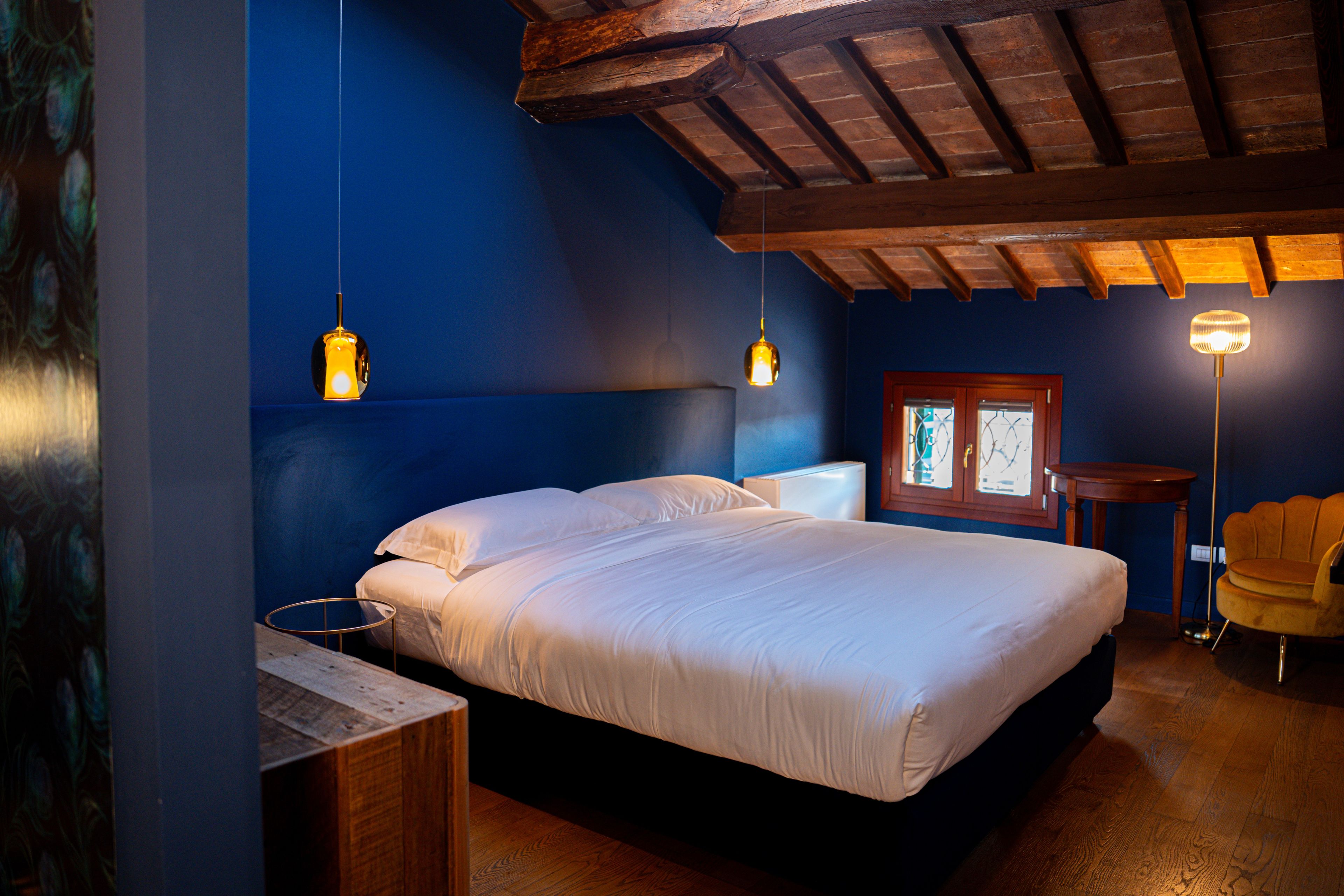 Ein Schlafzimmer mit einem Bett, Nachttischen, einem Sessel und Pendelleuchten.