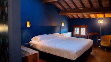 Ein Schlafzimmer mit einem Bett, Nachttischen, einem Sessel und Pendelleuchten.