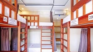 A bunk bed room with wooden railings, numbered beds, and curtains. - Castaway Hostel (Badung)