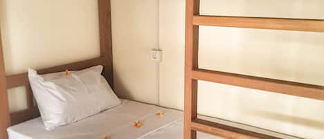 A bunk bed with a wooden frame, a single bed on the lower bunk, and a small drawer under the lower bunk.