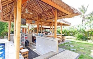 Un espacio exterior techado con piscina, bar y asientos.
