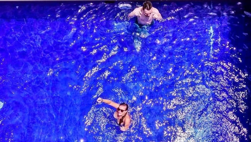 A swimming pool with two people in the water.