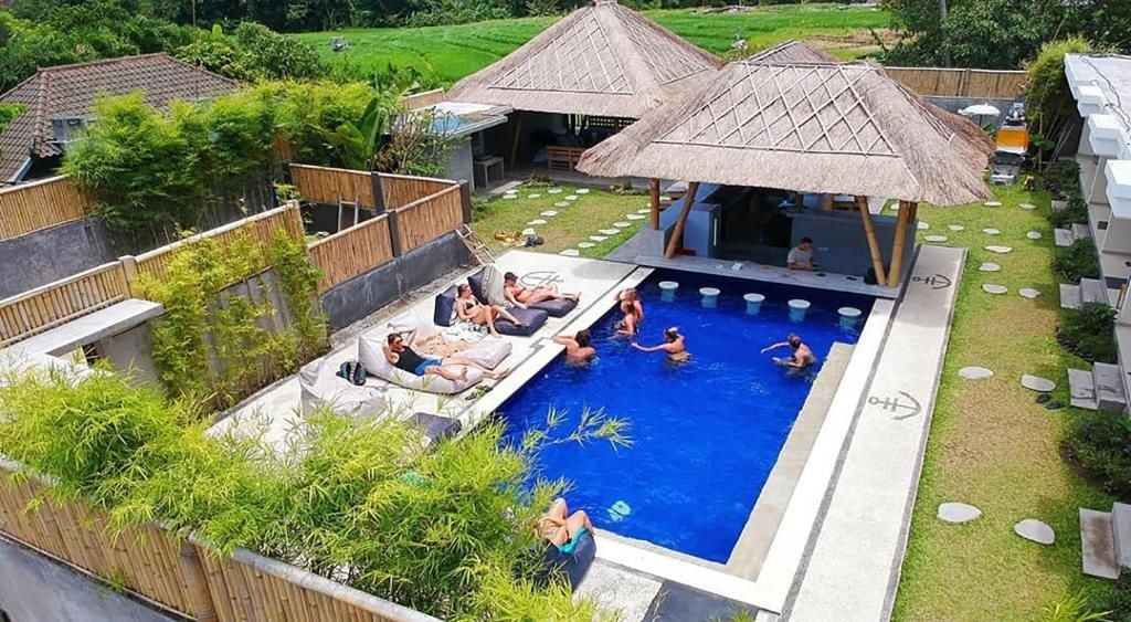 A swimming pool area with lounge chairs and a thatched-roof structure.