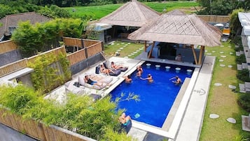 A swimming pool area with lounge chairs and a thatched-roof structure.