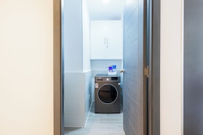 Ein Waschraum mit Waschmaschine, Schrank und Wasserspender.