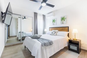Ein modernes Schlafzimmer mit einem Bett, Nachttischen, einem Deckenventilator und Kunstwerken an den Wänden.