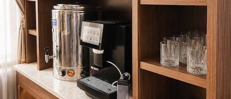 Una estación de café con una máquina de café, tazas y una bandeja de cápsulas de café.