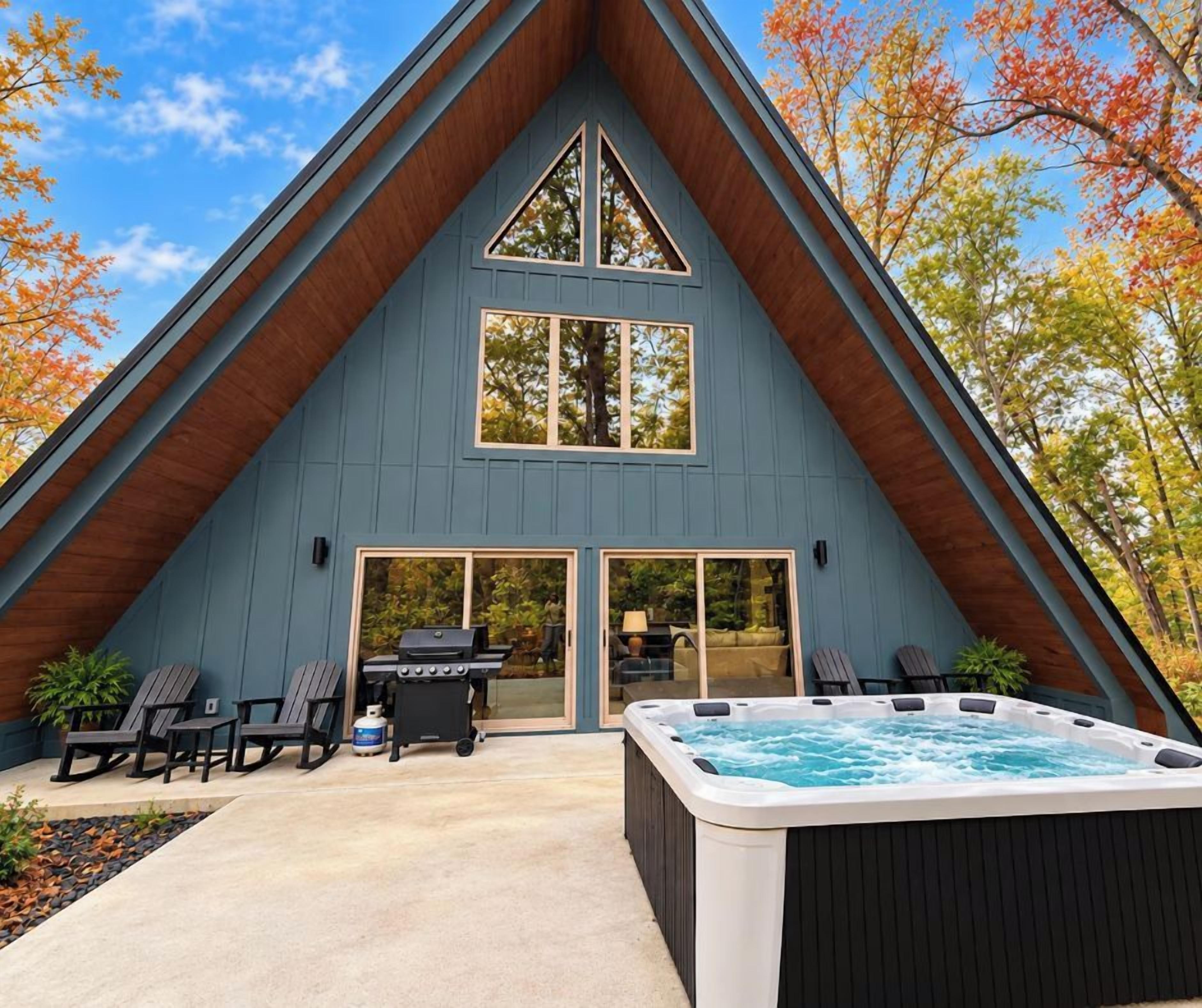 A modern house with a triangular roof, a hot tub, and outdoor seating.