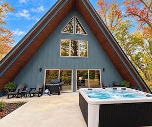 A modern house with a triangular roof, a hot tub, and outdoor seating. - Brand new three bedroom three bathroom A-Frame Cabin (Sevierville)
