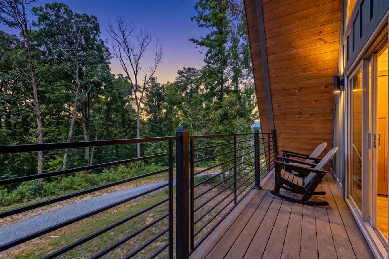 A wooden deck with a railing, overlooking a forested area.