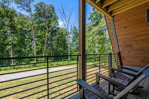 A wooden cabin with a balcony overlooking a road and forest. - Brand new three bedroom three bathroom A-Frame Cabin (Sevierville)