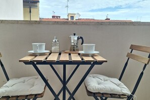A wooden table with two white cups and a coffee maker, set against a plain wall with a view of buildings in the background. - Il Nido di Artemisia - Relaxing Florentine home (Florence)
