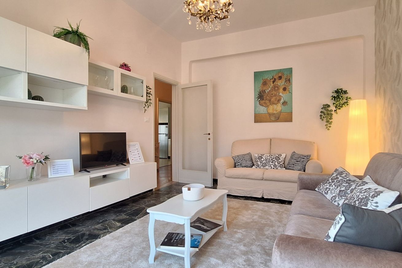 A modern living room with a sofa, a television, a coffee table, and a painting on the wall.