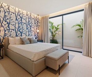 Ein modernes Schlafzimmer mit einem großen Bett, einer Bank, einem Nachttisch und einer Wand mit einem einzigartigen Muster.