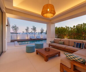 Ein moderner Außenbereich mit Lounge-Möbeln, Pool und einer hängenden Leuchte.