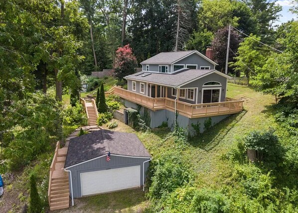 Ein zweistöckiges Haus mit einer Terrasse, umgeben von üppigem Grün.