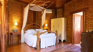 Een kamer met een bed, een kledingkast, een tafel en een lamp.
