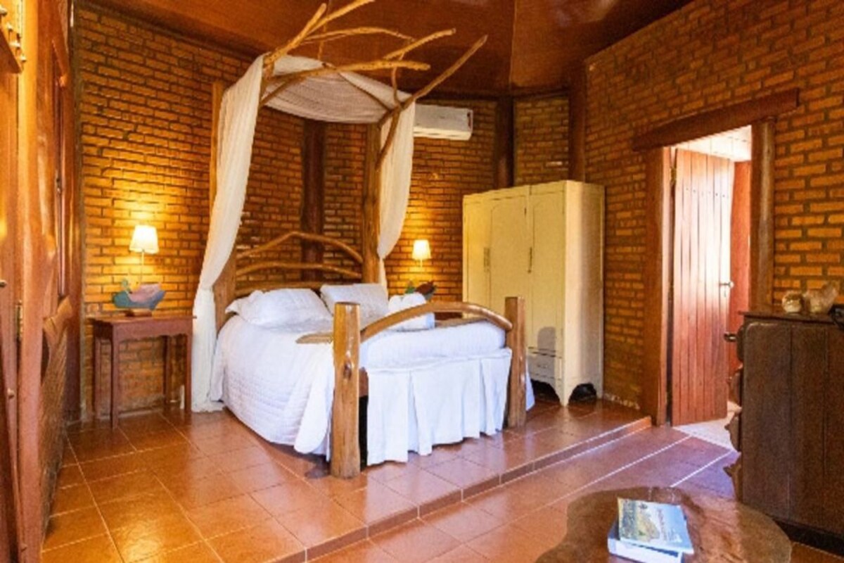 A room with a bed, a wardrobe, a table, and a lamp.