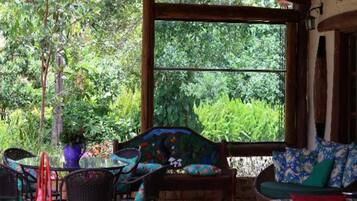 An outdoor seating area with wicker furniture and a view of lush greenery.