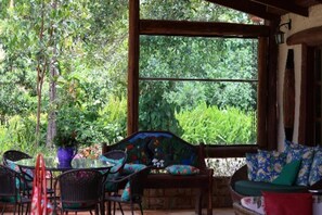 An outdoor seating area with wicker furniture and a view of lush greenery. - Pousada Fazenda São Bento (Alto Paraíso de Goiás)