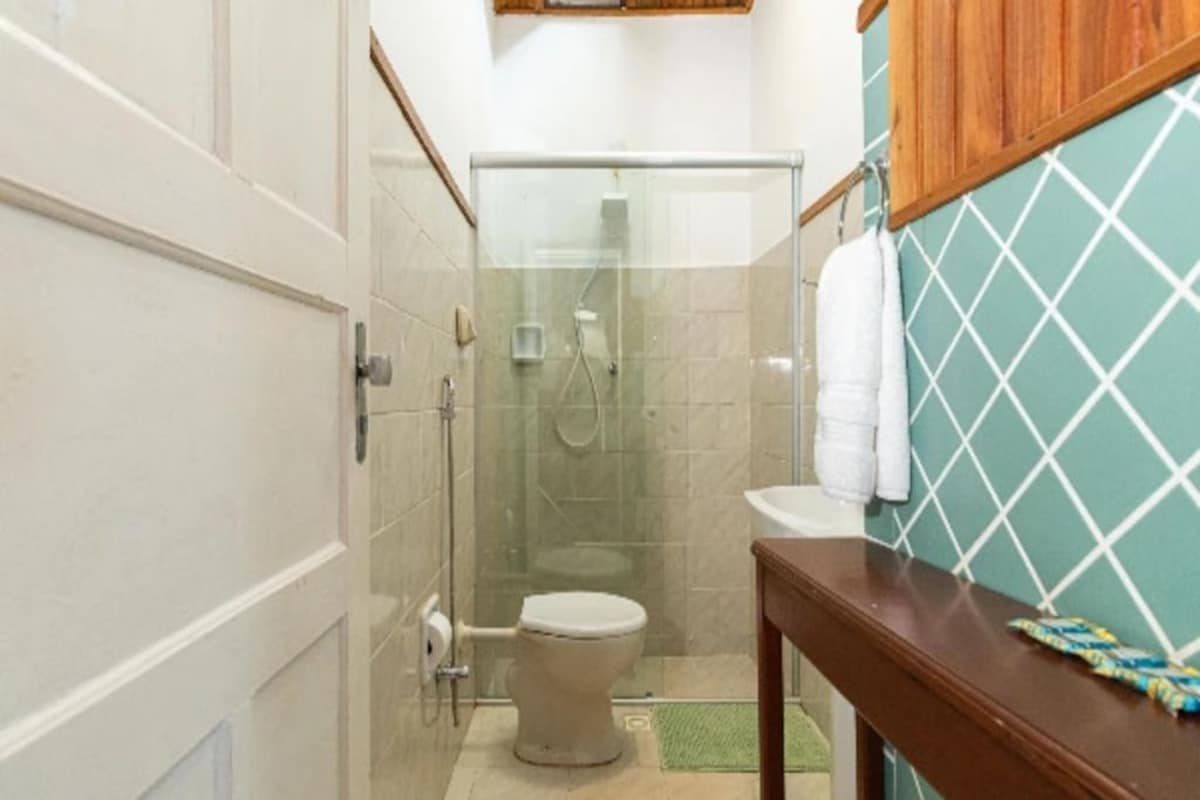 A bathroom with a glass-enclosed shower, a toilet, and a sink with a wooden countertop.