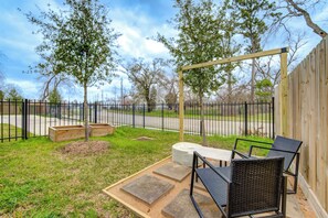 An outdoor patio with a wooden pergola, a seating area with chairs, and a garden with trees and a fence. - Gated 3BR Home, Garage + Fenced Backyard, 15 Min to Galleria & Downtown (Houston)