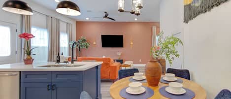 A modern kitchen with blue cabinets, a wooden dining table, and a ceiling fan.