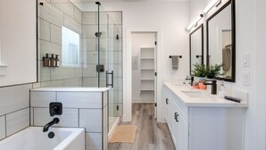 A modern bathroom with a glass shower enclosure, a bathtub, and a vanity with a mirror. - Gated 3BR Home, Garage + Fenced Backyard, 15 Min to Galleria & Downtown (Houston)
