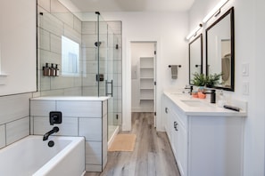 A modern bathroom with a glass shower enclosure, a bathtub, and a vanity with a mirror. - Gated 3BR Home, Garage + Fenced Backyard, 15 Min to Galleria & Downtown (Houston)