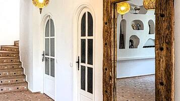 Un couloir doté d’un sol à motifs, d’un miroir encadré en bois et de lampes suspendues.