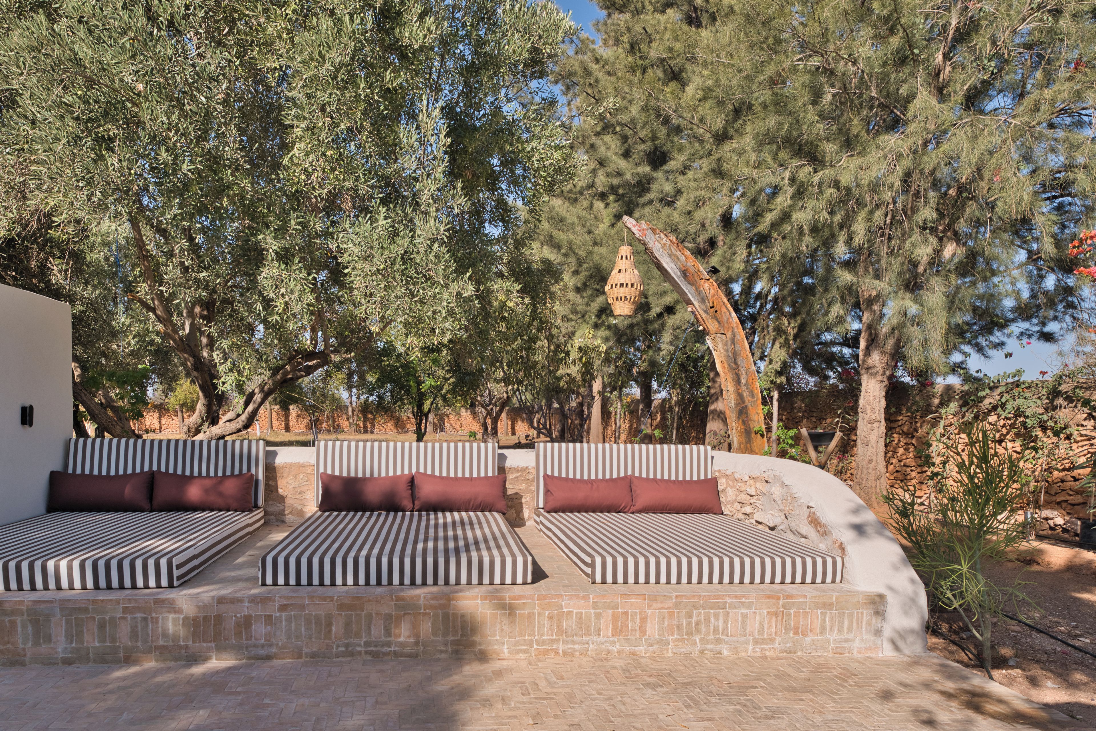 Una terraza con tres sillones lounge a rayas y un muro de piedra.