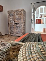 Una habitaci ón con un armario de madera rústica, una cama con una colcha verde y una cesta de mimbre.