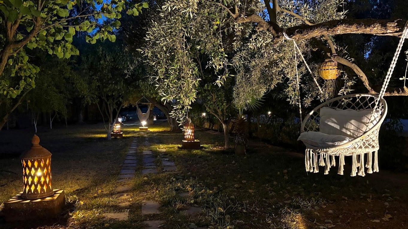 A garden with a swing chair, lanterns, and a pathway.